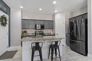 Kitchen with stainless steel appliances, light stone counters, a sink, light wood-style flooring, and recessed lighting