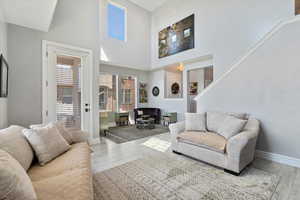 Living area with baseboards, wood finished floors, and a high ceiling