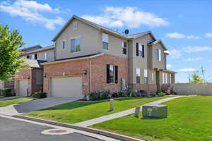 View of property with an attached garage, driveway, stucco siding, and brick siding