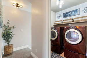 Laundry area featuring washing machine and clothes dryer, baseboards, and carpet floors