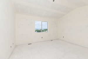 Spare room featuring vaulted ceiling and baseboards