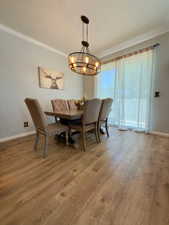 Dining area featuring crown molding, a chandelier, hardwood / wood-style flooring, and baseboards