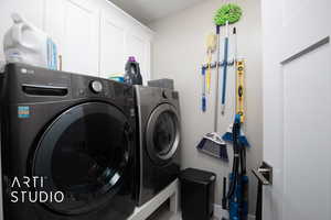 Laundry room featuring washing machine and dryer, cabinet space, and baseboards