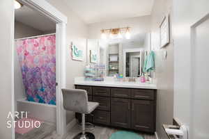 Bathroom featuring wood finished floors, vanity, shower / bath combination with curtain, and baseboards