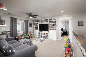 Carpeted living area with ceiling fan, a textured ceiling, recessed lighting, and baseboards