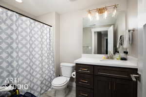 Bathroom featuring toilet, vanity, and curtained shower