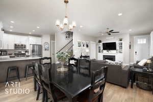 Dining area with light wood finished floors, a ceiling fan, recessed lighting, stairs, and a chandelier