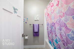 Full bathroom with baseboards and shower / bath combo with shower curtain