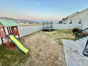 View of yard featuring a trampoline and a playground