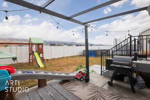 View of patio with a playground and area for grilling