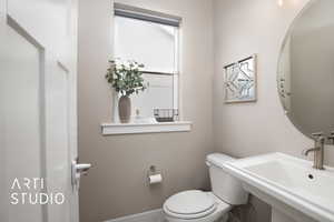 Bathroom with toilet, a sink, and baseboards