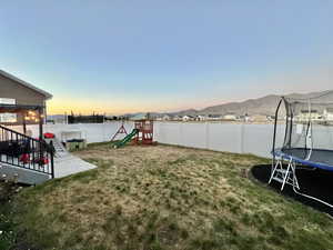 Yard at dusk with a trampoline and a playground
