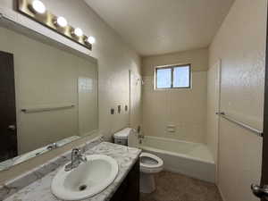 Bathroom with toilet, a textured wall, vanity, and tub / shower combination