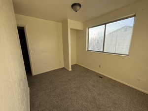 Unfurnished bedroom featuring dark colored carpet and baseboards