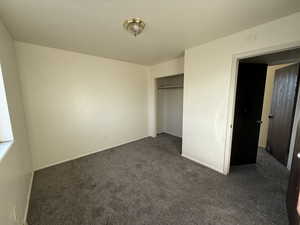 Unfurnished bedroom with dark colored carpet and a closet