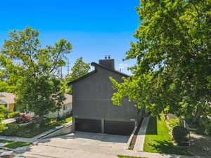 View of side of home featuring an attached garage, driveway, and a chimney