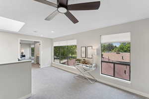 Carpeted living room with plenty of natural light, baseboards, a skylight, a ceiling fan, and recessed lighting