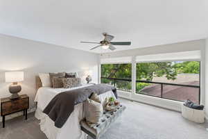 Carpeted bedroom featuring multiple windows and a ceiling fan