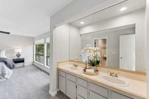 Bathroom featuring double vanity, baseboards, and recessed lighting