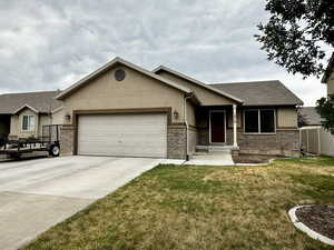 Single story home with an attached garage, concrete driveway, and brick siding