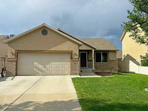 View of front facade featuring an attached garage, driveway, stucco siding, and brick siding