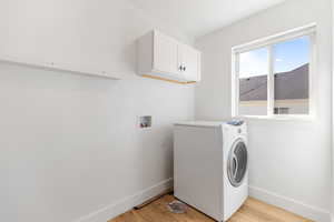 Laundry area featuring washer / clothes dryer, cabinet space, baseboards, and light wood finished floors