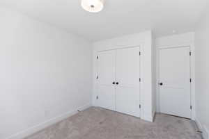 Unfurnished bedroom with carpet flooring, baseboards, and a closet