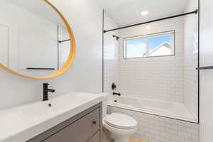 Full bathroom featuring tiled shower / bath combo, toilet, vanity, and recessed lighting