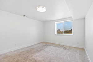 Carpeted spare room featuring baseboards