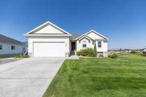 Single story home with a garage, board and batten siding, concrete driveway, and a front lawn