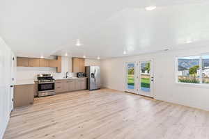 Basement kitchen featuring appliances with stainless steel finishes, a sink, light wood-style flooring, plenty of natural light, and recessed lighting
