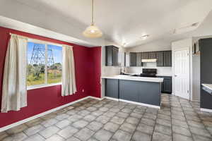 Kitchen with black electric range, under cabinet range hood, light countertops, a peninsula, and baseboards