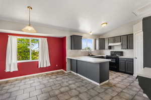 Kitchen with black / electric stove, under cabinet range hood, light countertops, a peninsula, and a textured ceiling