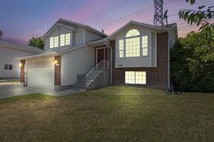 Split level home with brick siding, driveway, a yard, and a garage