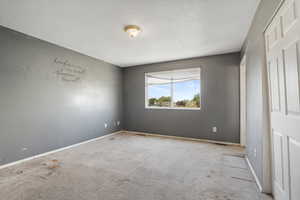 Unfurnished bedroom with a textured ceiling, carpet, and baseboards