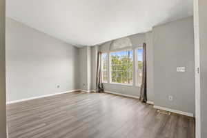 Spare room with wood finished floors, a textured ceiling, and baseboards