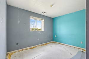 Empty room with a textured ceiling and baseboards