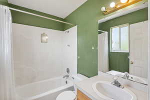 Bathroom with vanity, shower / bathtub combination with curtain, and toilet