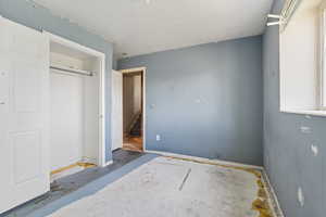Unfurnished bedroom with a textured ceiling, a closet, and baseboards