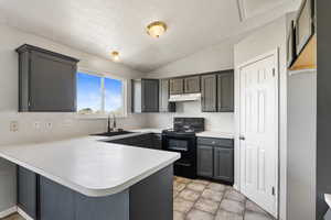 Kitchen featuring electric range, a sink, under cabinet range hood, a peninsula, and light countertops