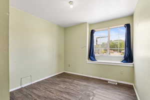 Spare room featuring wood finished floors, a textured ceiling, and baseboards