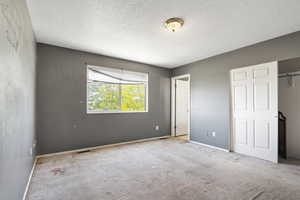 Unfurnished bedroom featuring a textured ceiling, carpet floors, baseboards, and a closet