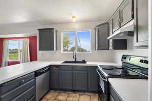 Kitchen with range with electric cooktop, stainless steel dishwasher, under cabinet range hood, a sink, and light countertops