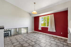 Unfurnished room featuring baseboards and lofted ceiling