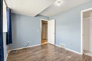 Unfurnished bedroom featuring wood finished floors, baseboards, and a textured ceiling