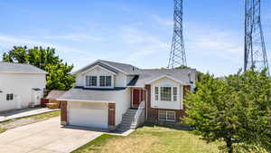 Split level home with brick siding, concrete driveway, a front lawn, roof with shingles, and a garage