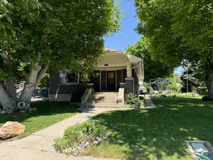 View of front of house featuring a front lawn, covered porch, and brick siding