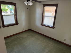 Carpeted empty room with a ceiling fan and baseboards
