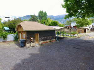 View of front facade featuring a mountain view, a carport, a shingled roof, dirt driveway, and brick siding