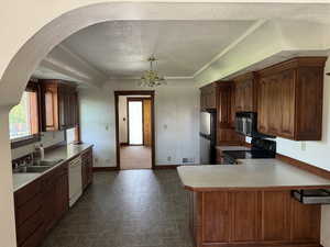 Kitchen featuring appliances with stainless steel finishes, a sink, a textured ceiling, baseboards, and arched walkways